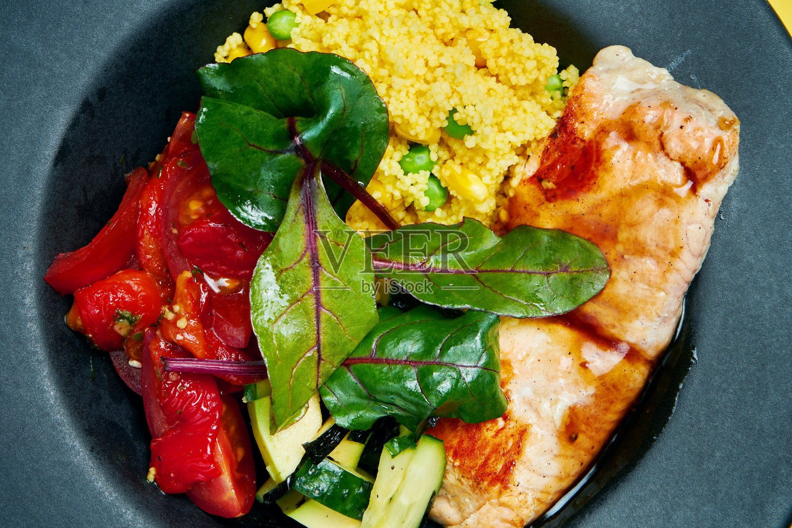 佛碗，配有三文鱼片，番茄干，菠菜，黄瓜和藜麦，黑色盘子，彩色背景。关闭了。锁的食物照片摄影图片