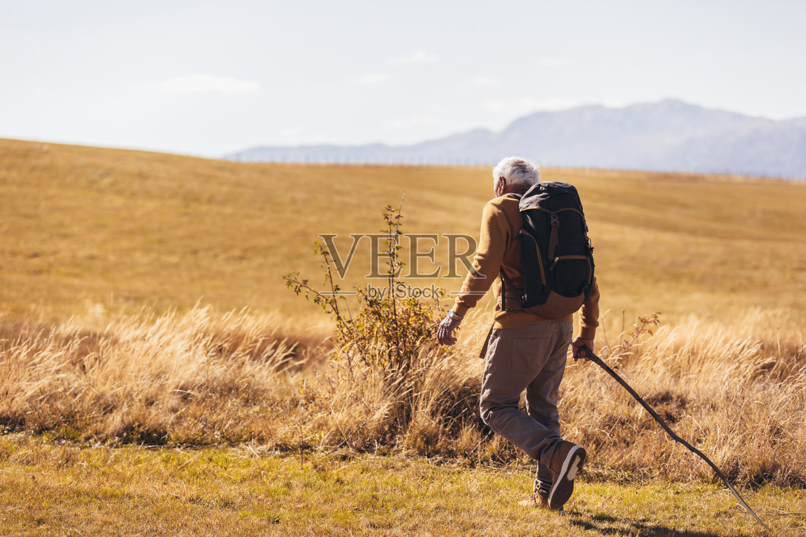 一位老人在秋天徒步穿越美丽的乡村。照片摄影图片