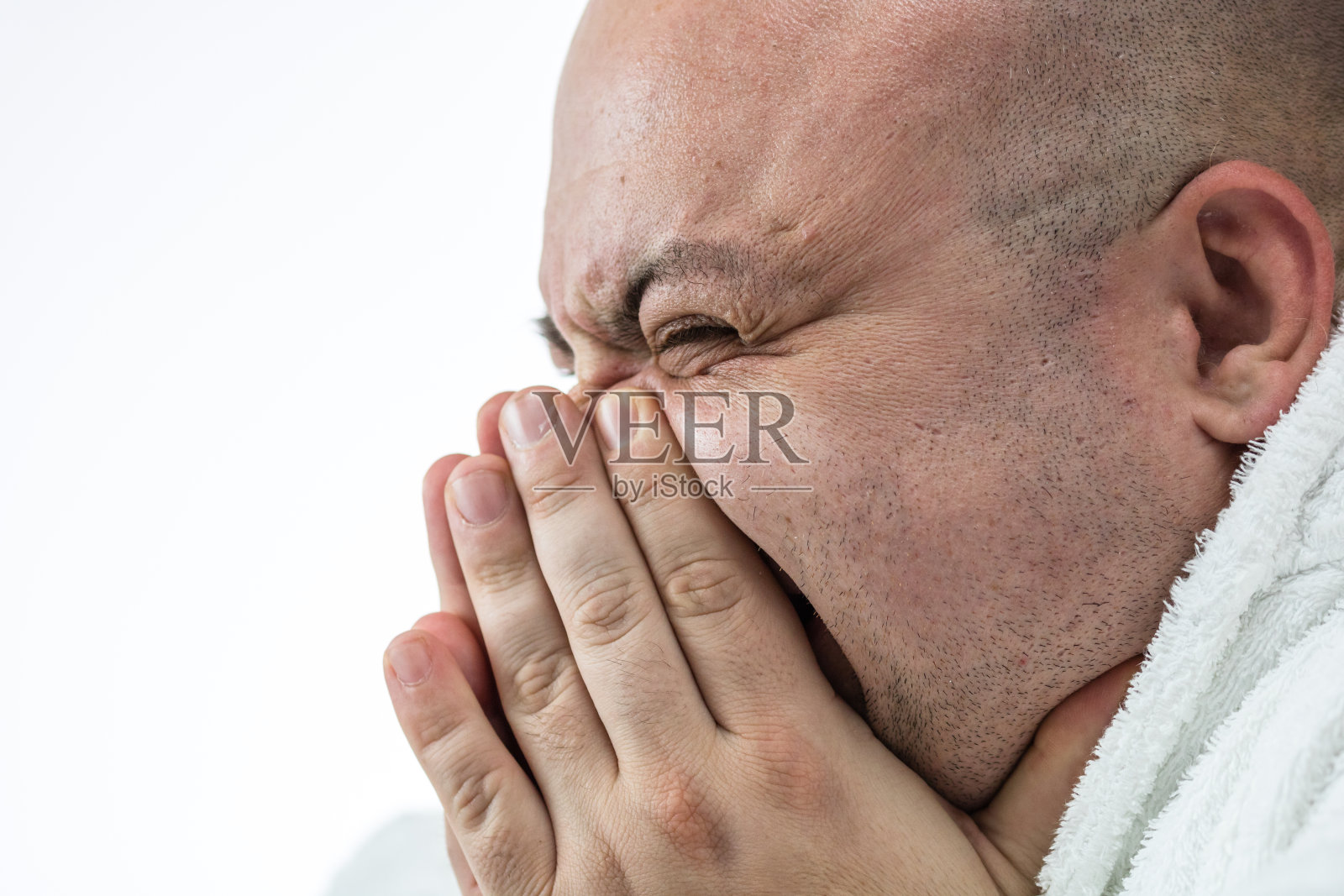 白种人生病的年轻男子打喷嚏由于Covid - 19病隔离在白色。Covid-19爆发、流感污染和医疗理念照片摄影图片