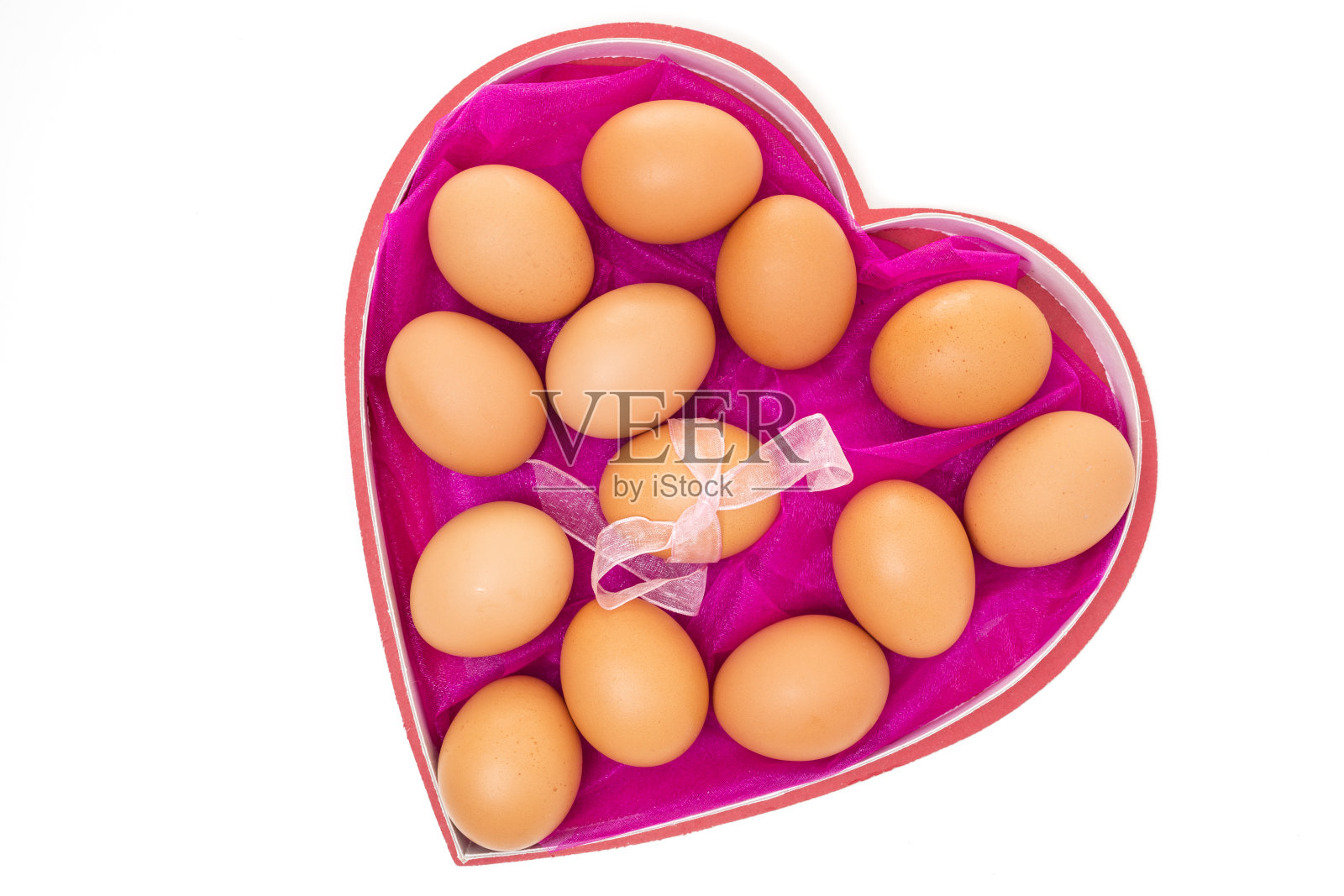棕色的鸡蛋在心形的盒子里，靠近孤立的白色背景。节日，复活节彩蛋概念照片摄影图片