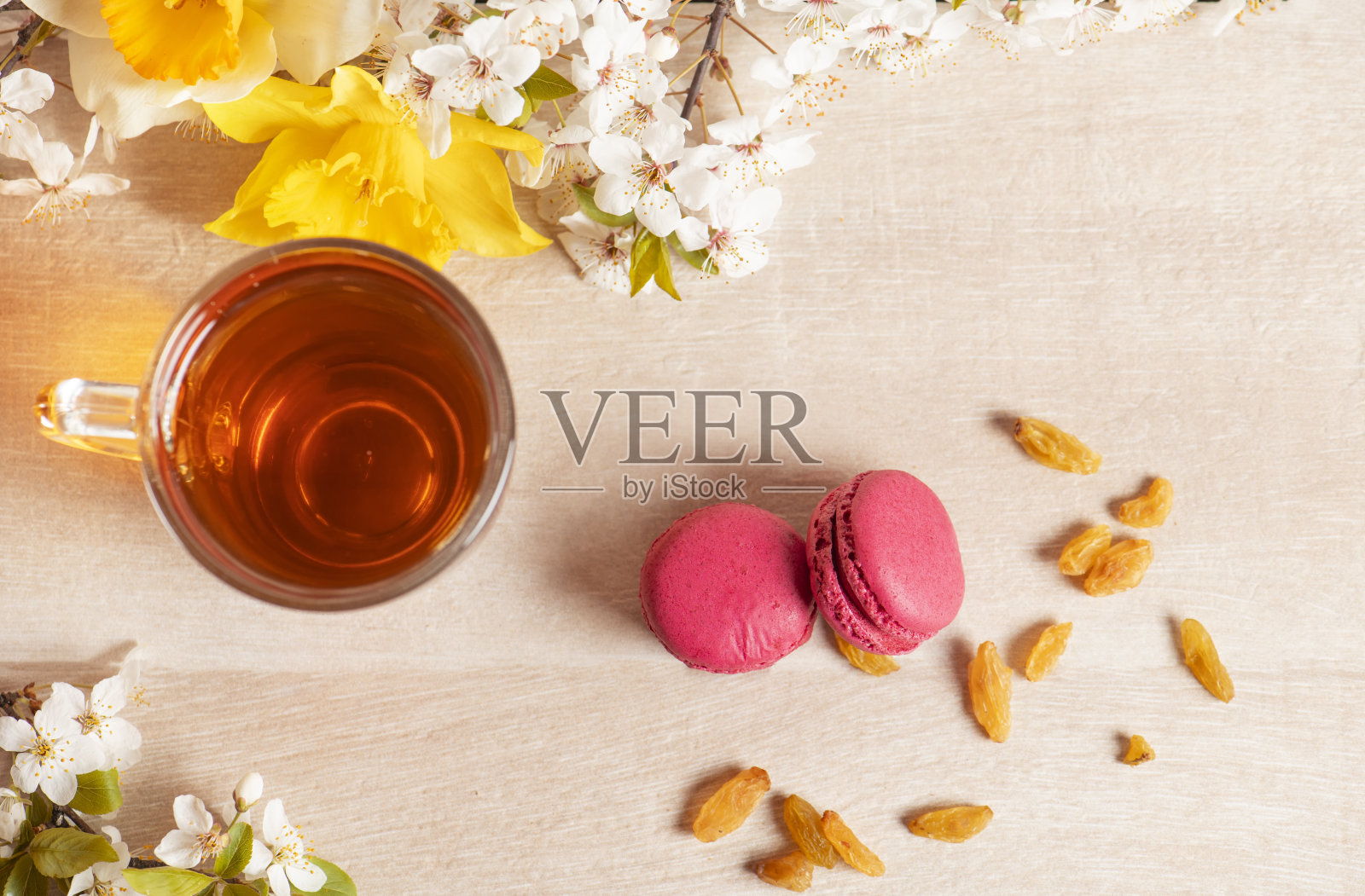 早上的早餐。一杯茶和红色的杏仁饼干在木制的背景和春天的鲜花。照片摄影图片