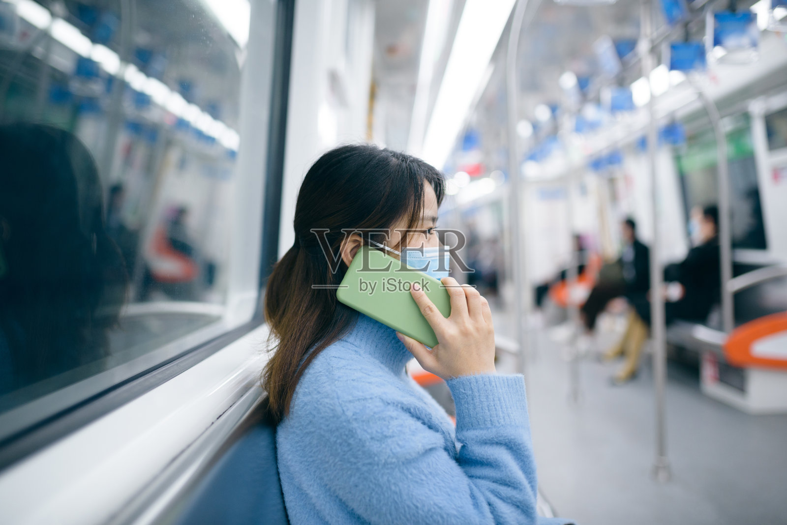 一位年轻女子在地铁里使用智能手机。照片摄影图片