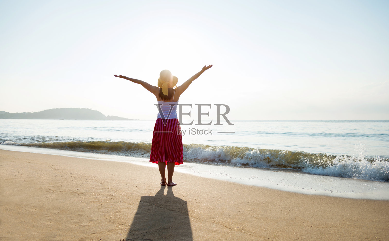 年轻女子高举双臂站在沙滩上照片摄影图片