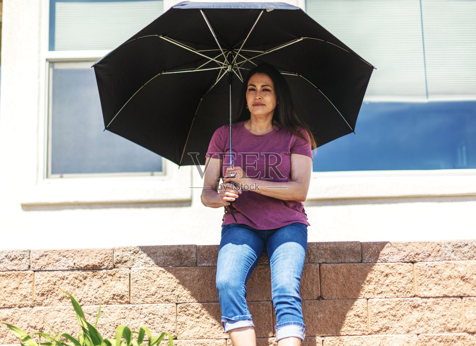 美丽的Pre - Senior成熟的成年女性在炎热的晴天坐在伞下照片摄影图片