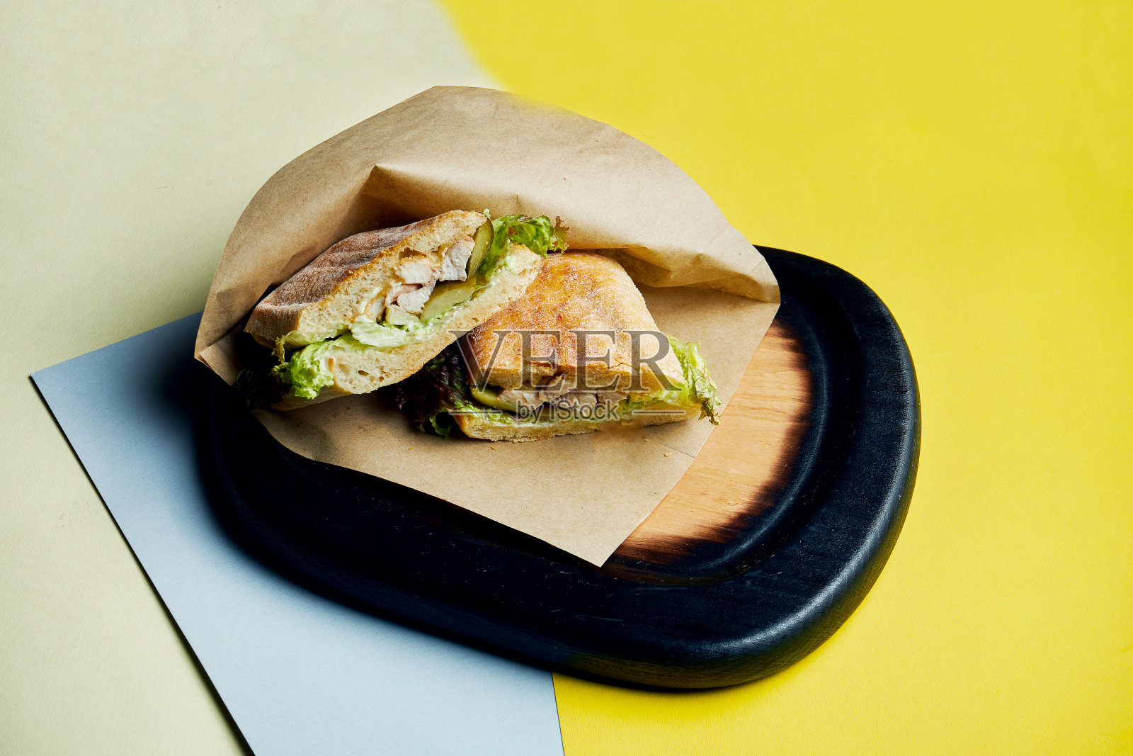 意大利脆皮面包夹三明治，木制托盘上有火腿、番茄、腌黄瓜奶酪和莴苣。关闭了。美味的快餐照片摄影图片