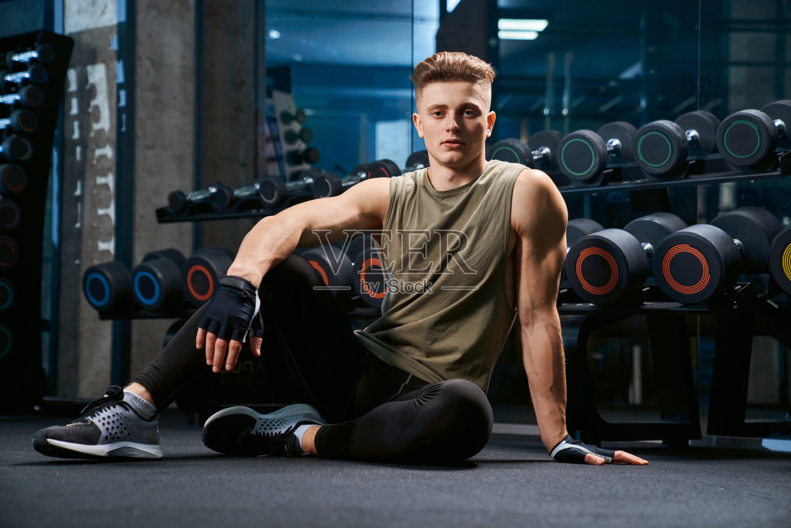 肌肉男在健身房的地板上摆姿势。照片摄影图片