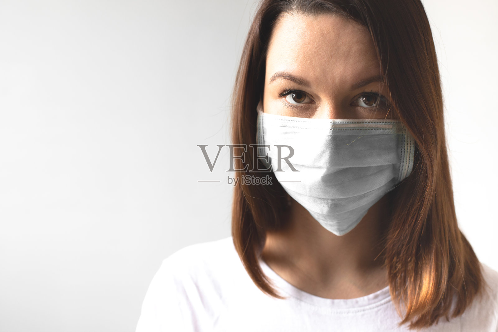 冠状病毒的概念。戴着医用防护口罩的女孩保护你的健康。遏制病毒和covid-19大流行。浅灰色背景照片摄影图片