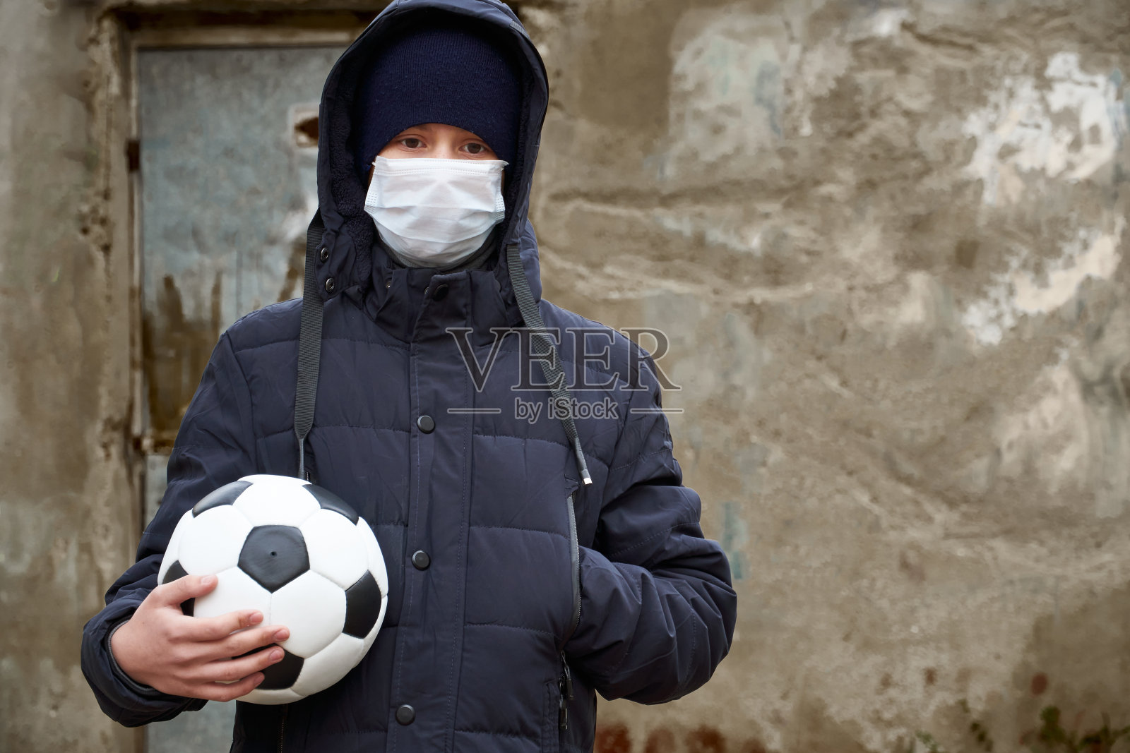 流行病和隔离的概念——一个男孩带着口罩和一个球独自在城市的街道上照片摄影图片