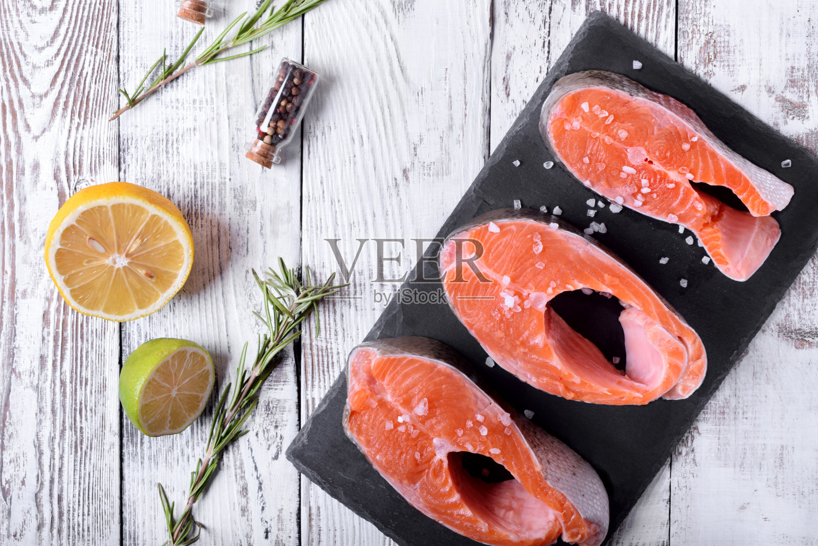 在生鳟鱼牛排上撒上海盐、柠檬汁和迷迭香照片摄影图片