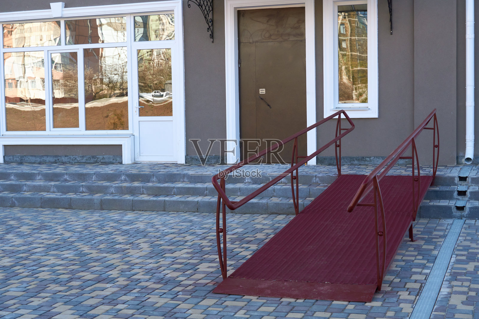 住宅多层建筑入口、城市街道及瓷砖人行道的轮椅入口坡道照片摄影图片