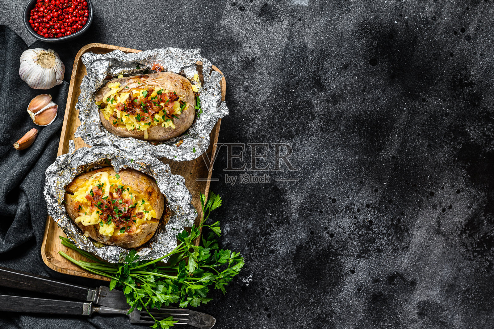 两个烤土豆配培根，葱和奶酪。黑色背景。前视图。本空间照片摄影图片