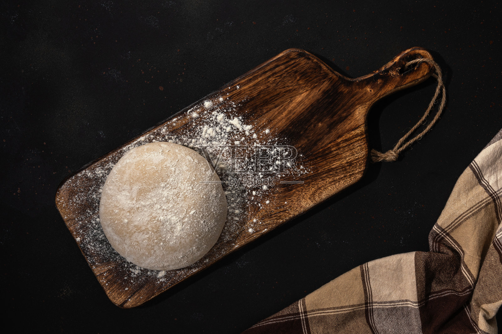 用新鲜生面团制作面包或披萨，在质朴的木质背景上撒上面粉。前视图。照片摄影图片