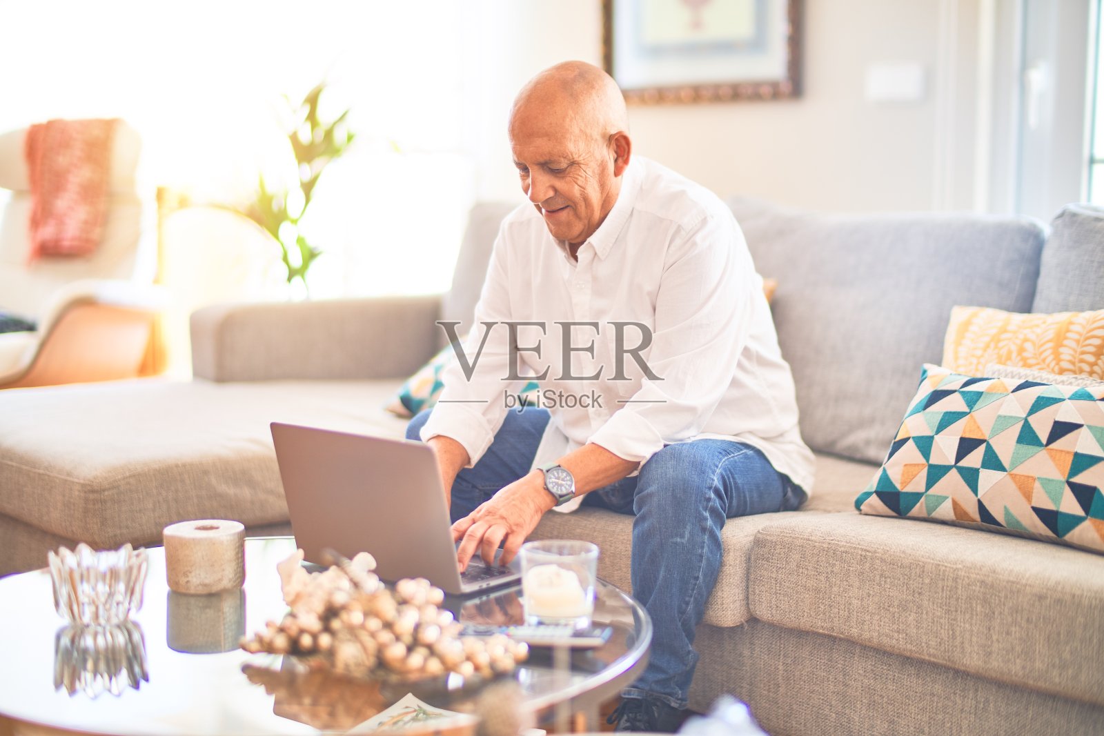 资深帅哥微笑快乐自信。坐在沙发上使用笔记本电脑照片摄影图片