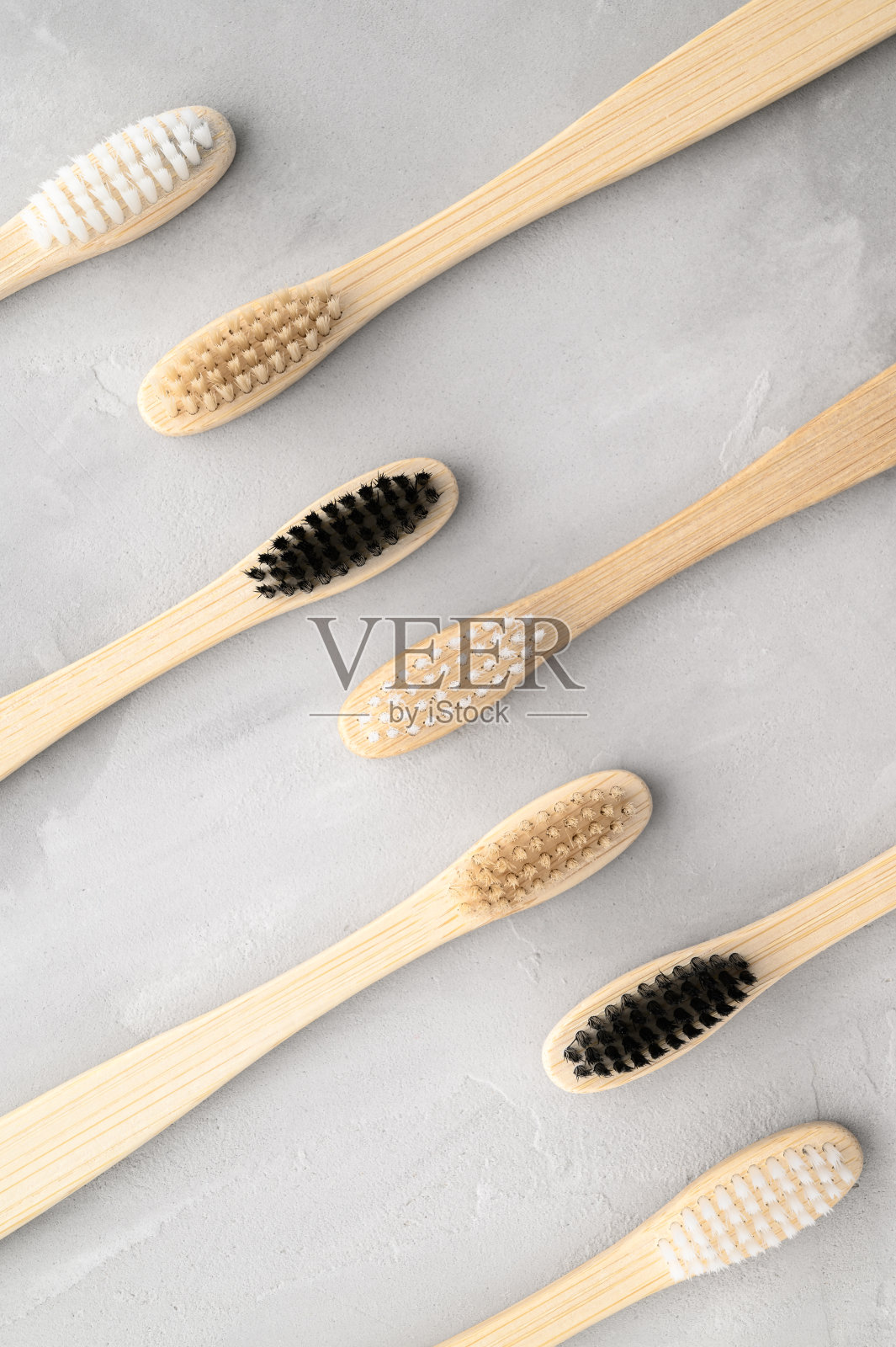 “零浪费”的概念。灰色混凝土背景上的环保竹制牙刷。照片摄影图片