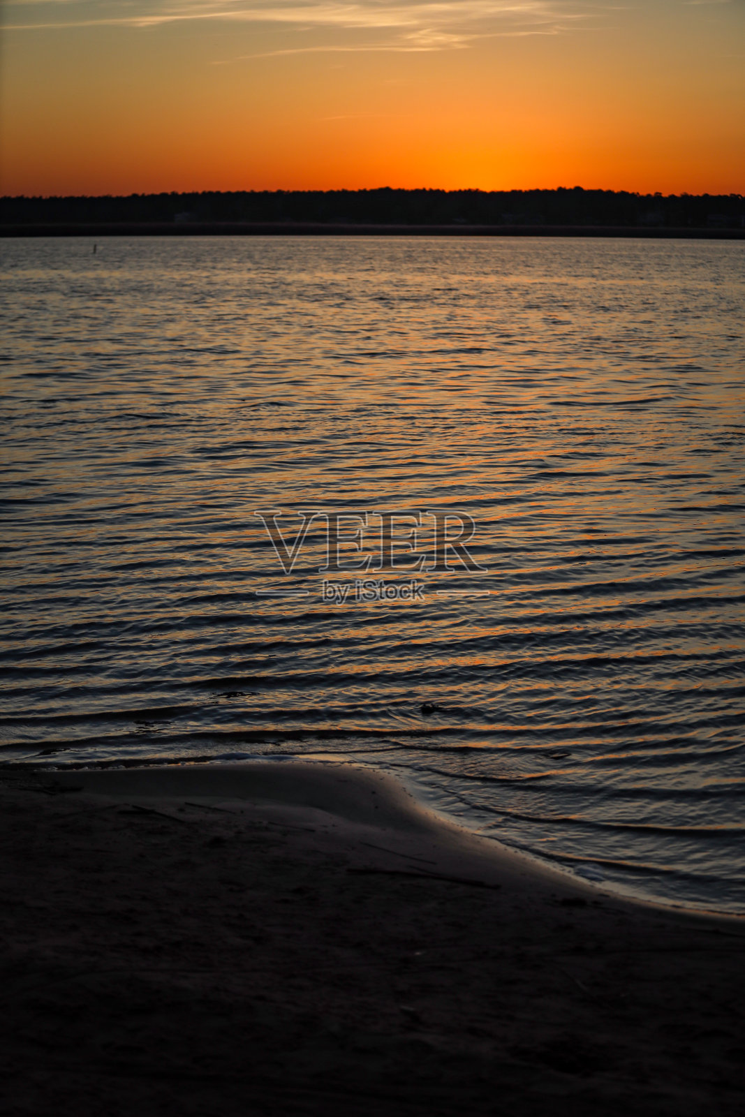 傍晚的河流日落与小波浪的水和橙黄色的天空。照片摄影图片