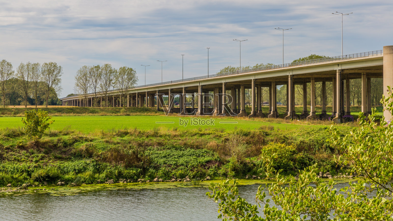 横跨马斯河的A76公路桥(Scharbergbrug)，田野上长满了绿草和树木照片摄影图片