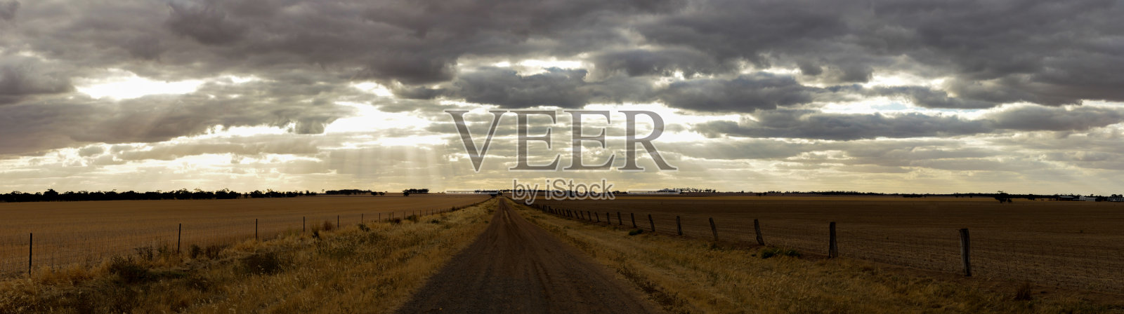 在维多利亚州乡村收获后的大片农田上，午后的天空中充满了戏剧性的乌云，中间是一条土路。照片摄影图片