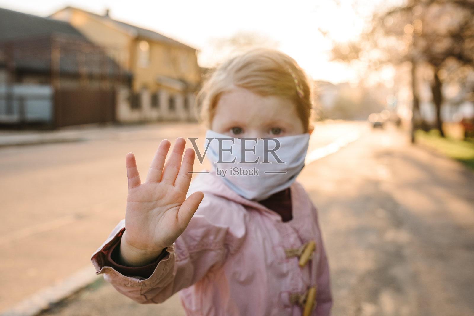 遏制冠状病毒和病毒传染病。健康儿童在医用防护口罩上显示手势停止。流感及传染病爆发期间的健康防护及预防。呆在家里。照片摄影图片