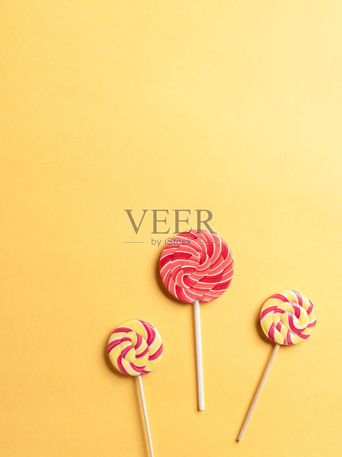 黄色背景上的三只棒棒糖。最小的概念。照片摄影图片
