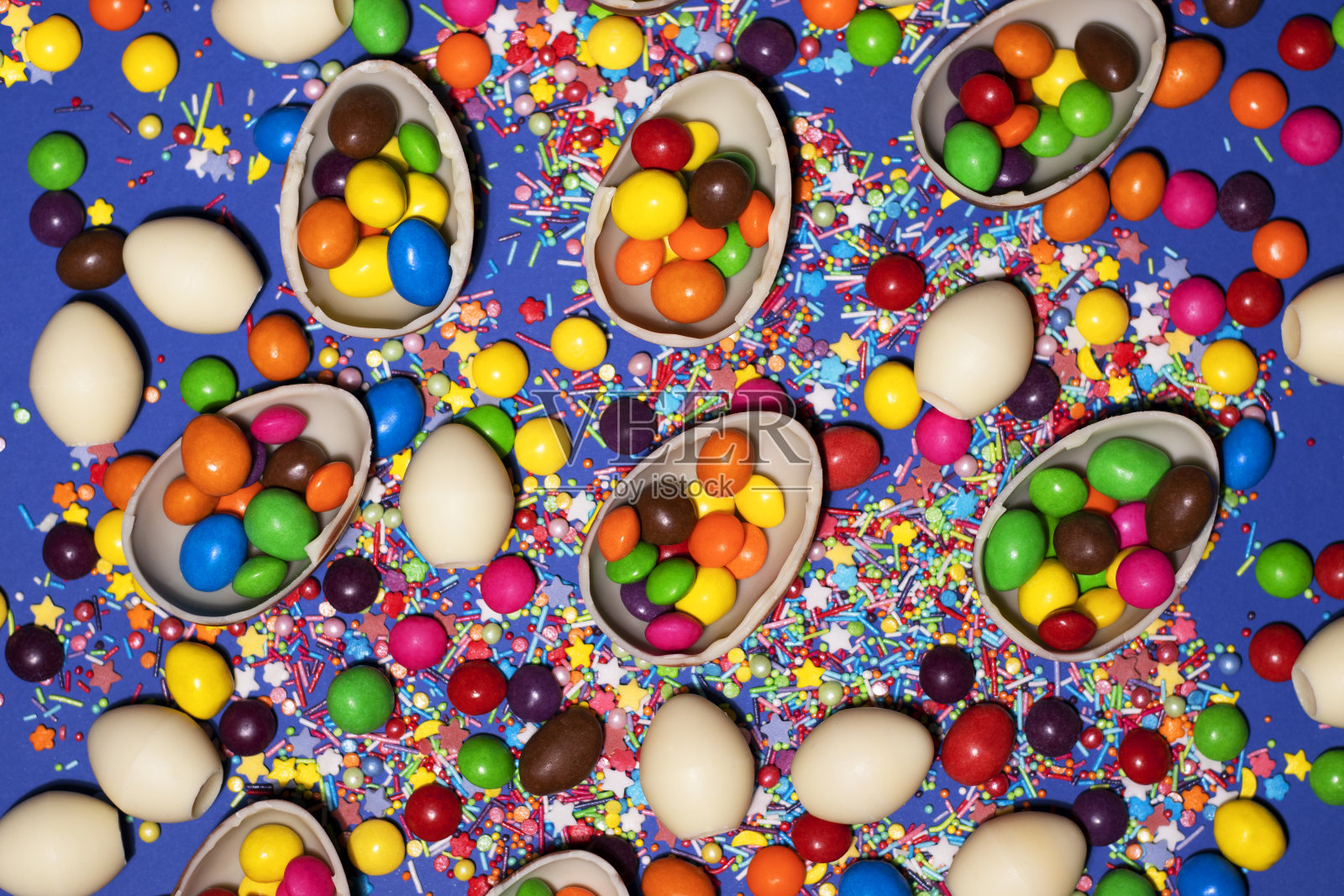 满是彩色果冻的半块巧克力蛋布满了蓝色的背景照片摄影图片