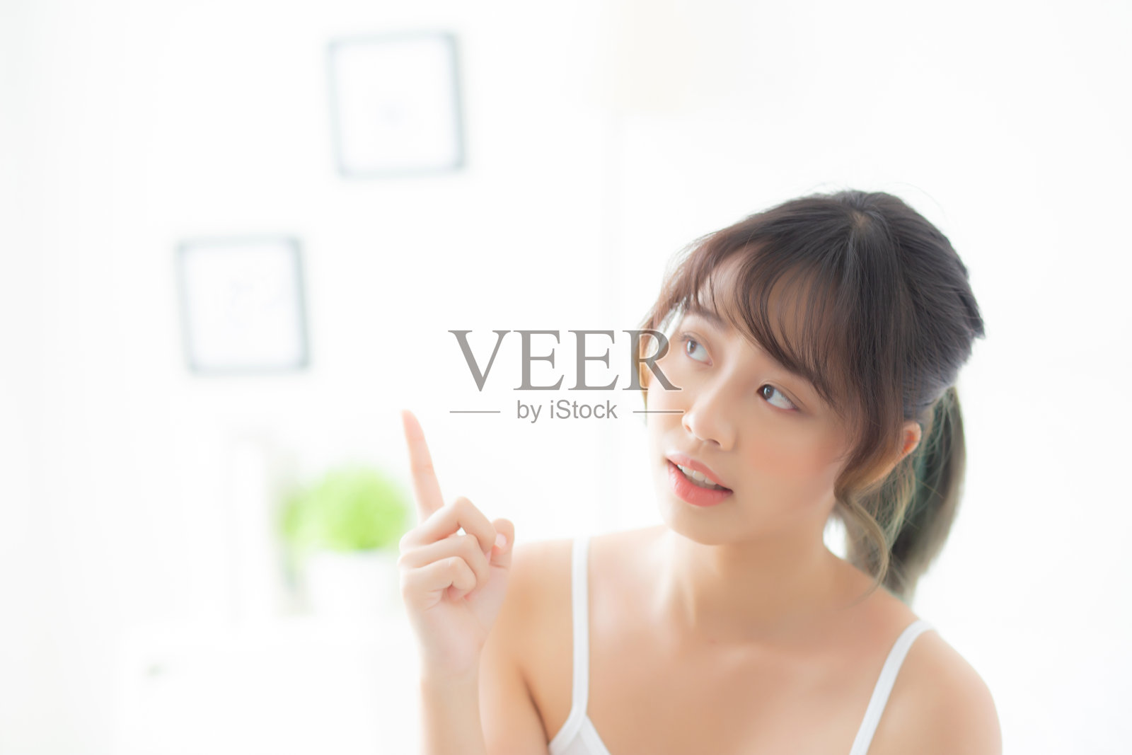 美丽的肖像年轻的亚洲女人微笑和健康的房间，美丽的亚洲女孩有想法呈现和指向一些皮肤护理和化妆化妆品，生活方式的概念。照片摄影图片