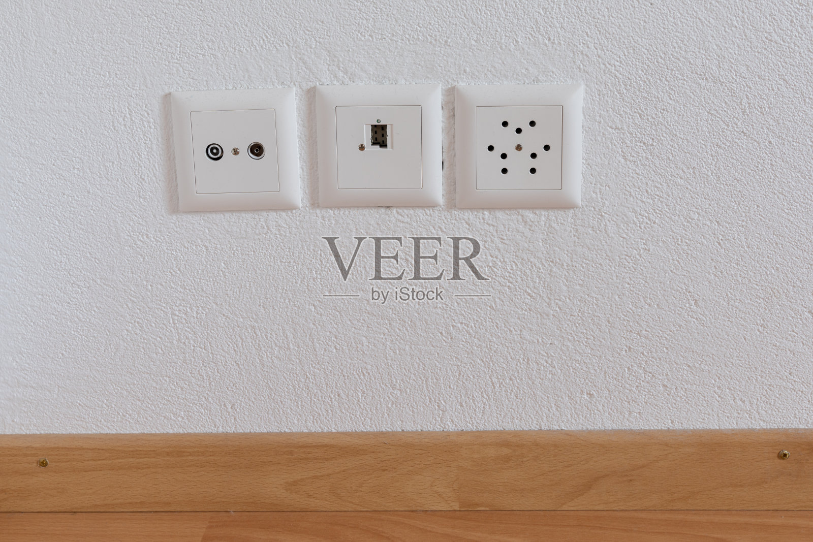 在白色墙壁和木地板上的电视、互联网、电话和电力插座的近景照片摄影图片