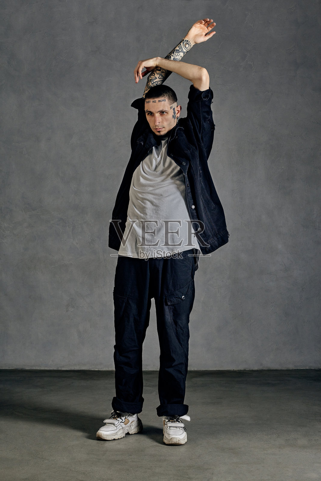 灵活的表演者，纹身的身体，胡子。穿着白t恤和运动鞋，黑衬衫，裤子。在灰色背景上跳舞。舞厅,嘻哈照片摄影图片