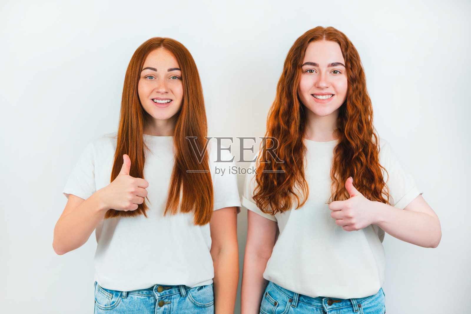 两个红头发的年轻女子看起来都很快乐，就像站在孤立的白色背景上的标志照片摄影图片