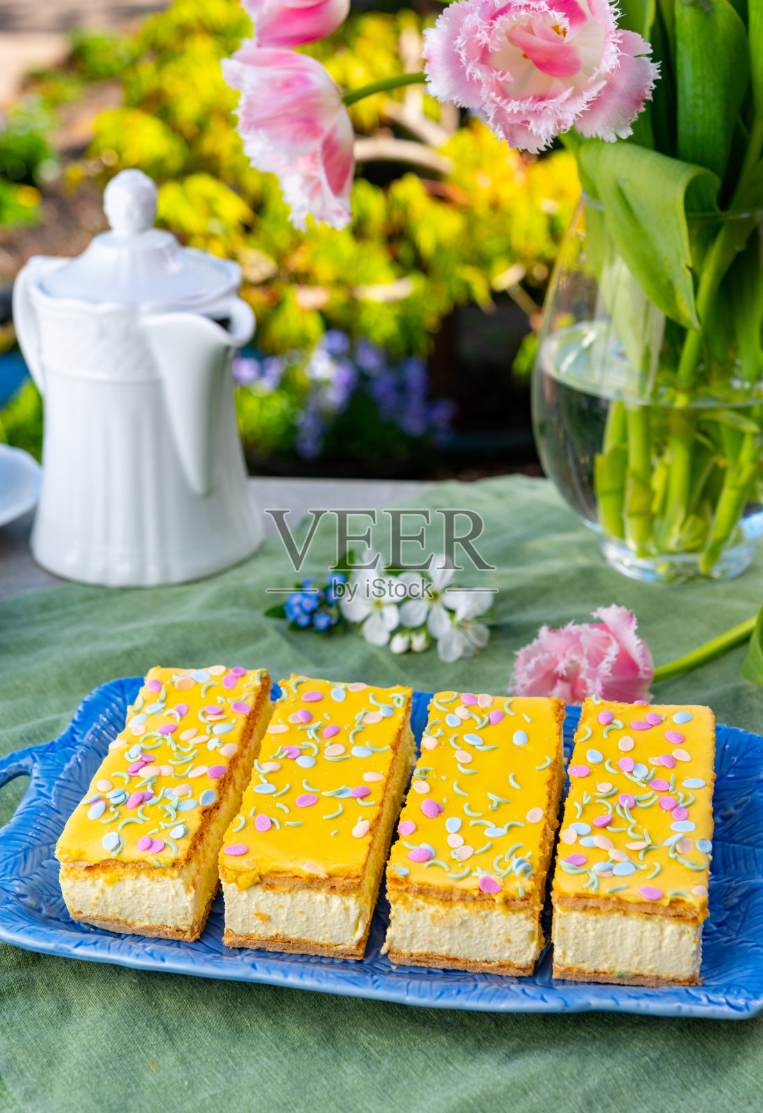 汤普斯蛋糕与鲜奶油和黄色糖霜在阳光明媚的春天花园照片摄影图片