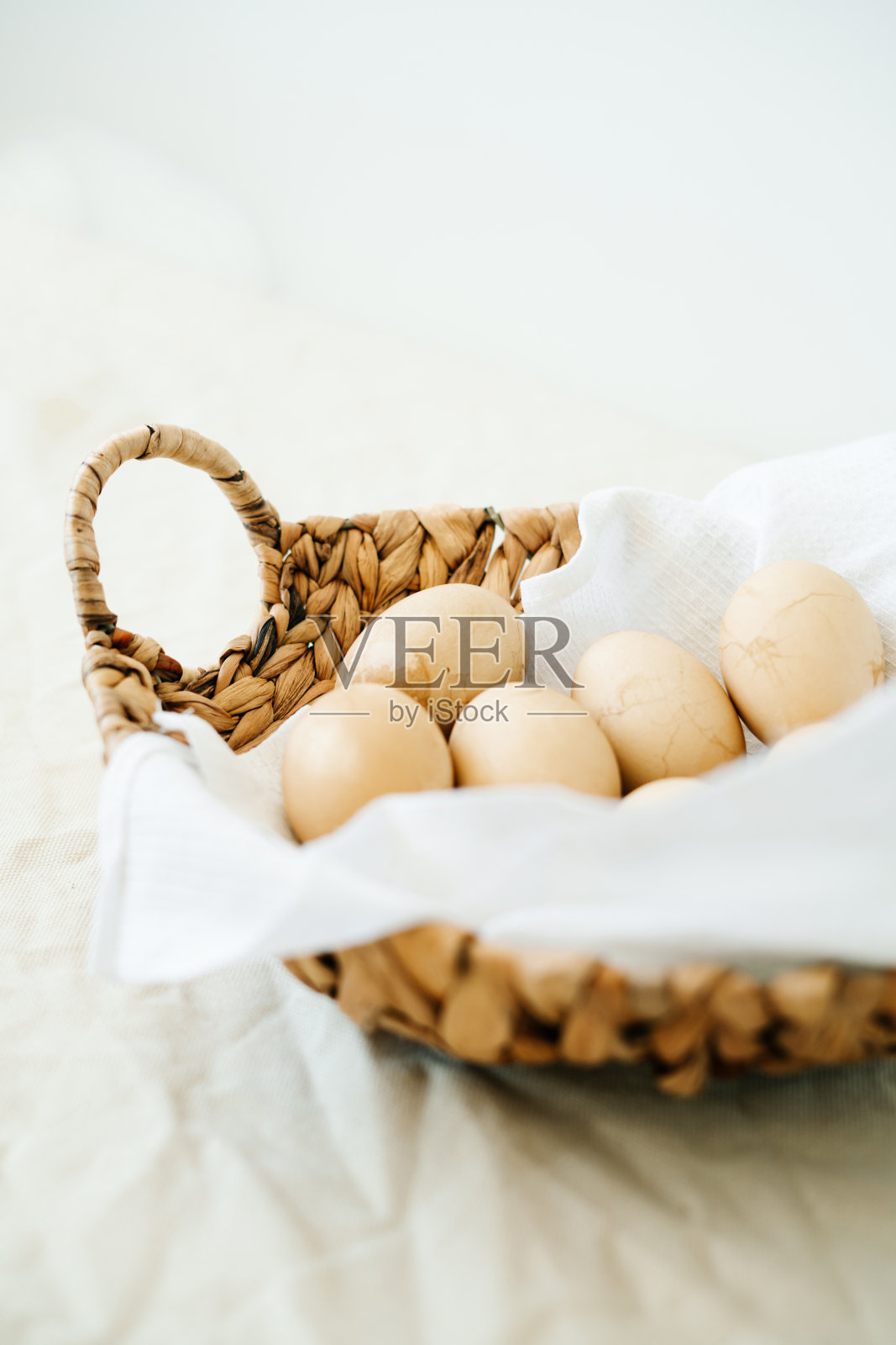 在一个由海藻制成的天然柳条篮子里，放着八个白色餐巾上有裂缝的复活节彩蛋，餐巾上是天然咖啡色。复活节快乐卡片与文本拷贝空间。复活节的概念。最小的风格。照片摄影图片