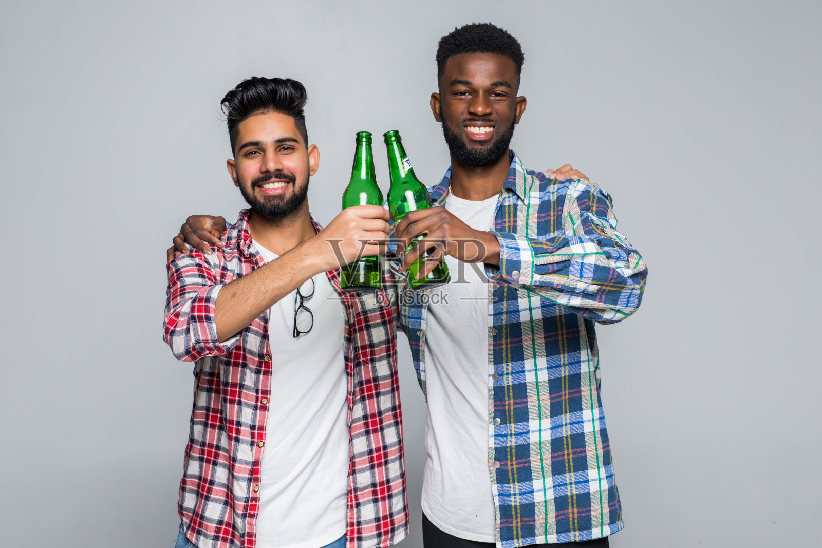 两个快乐的年轻人最好的朋友举杯庆祝在白色的背景孤立的啤酒瓶照片摄影图片