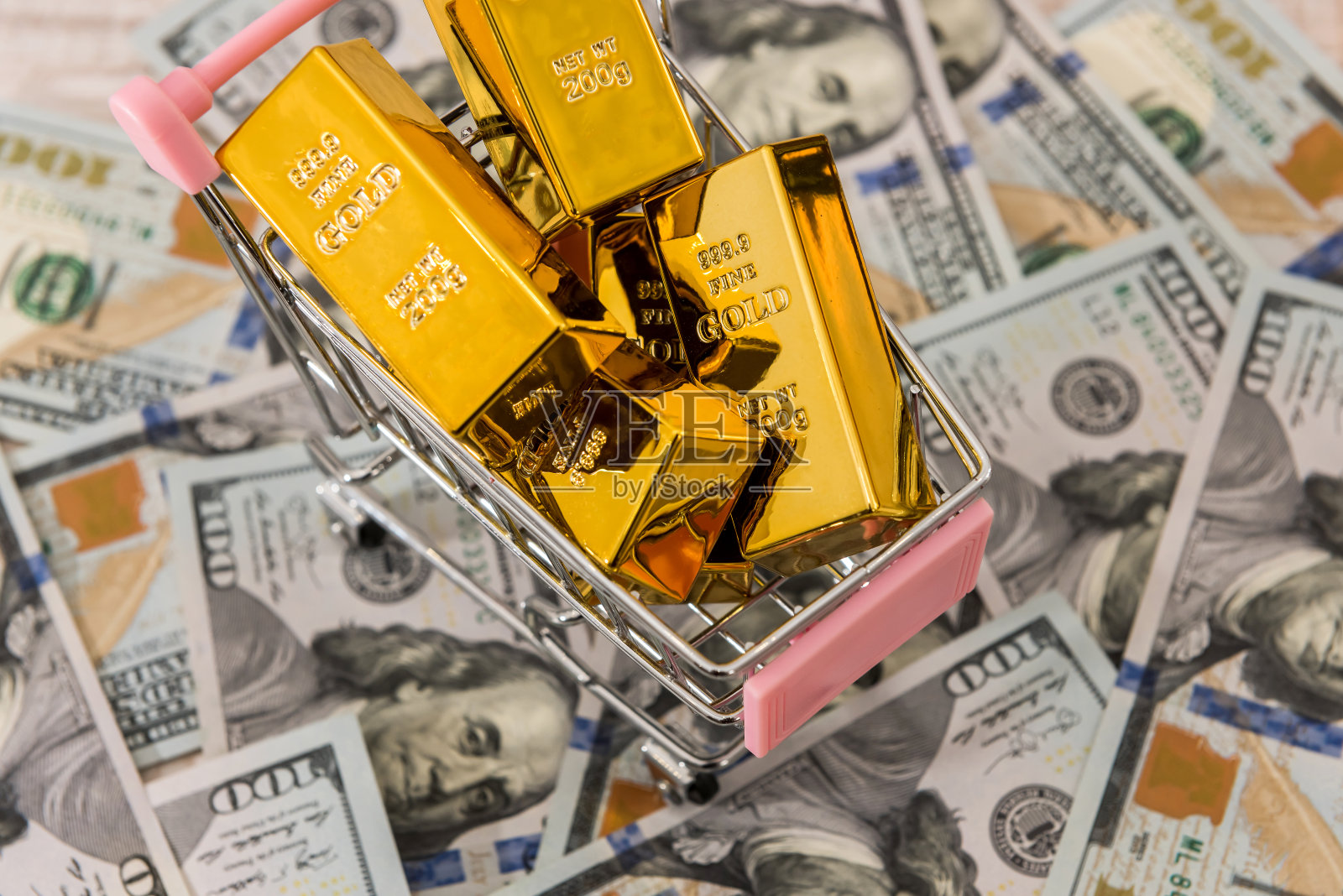 购物车里放着金条，背景是美元。金钱、财富和富足的概念。照片摄影图片