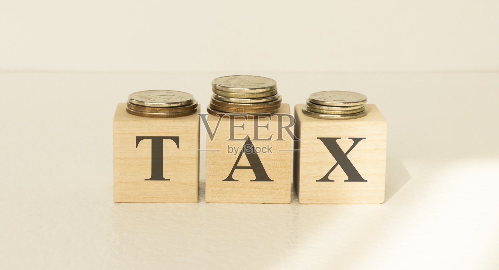 木立方体税字和钱币堆放在木桌的背景上。2020纳税日定于4月15日。照片摄影图片