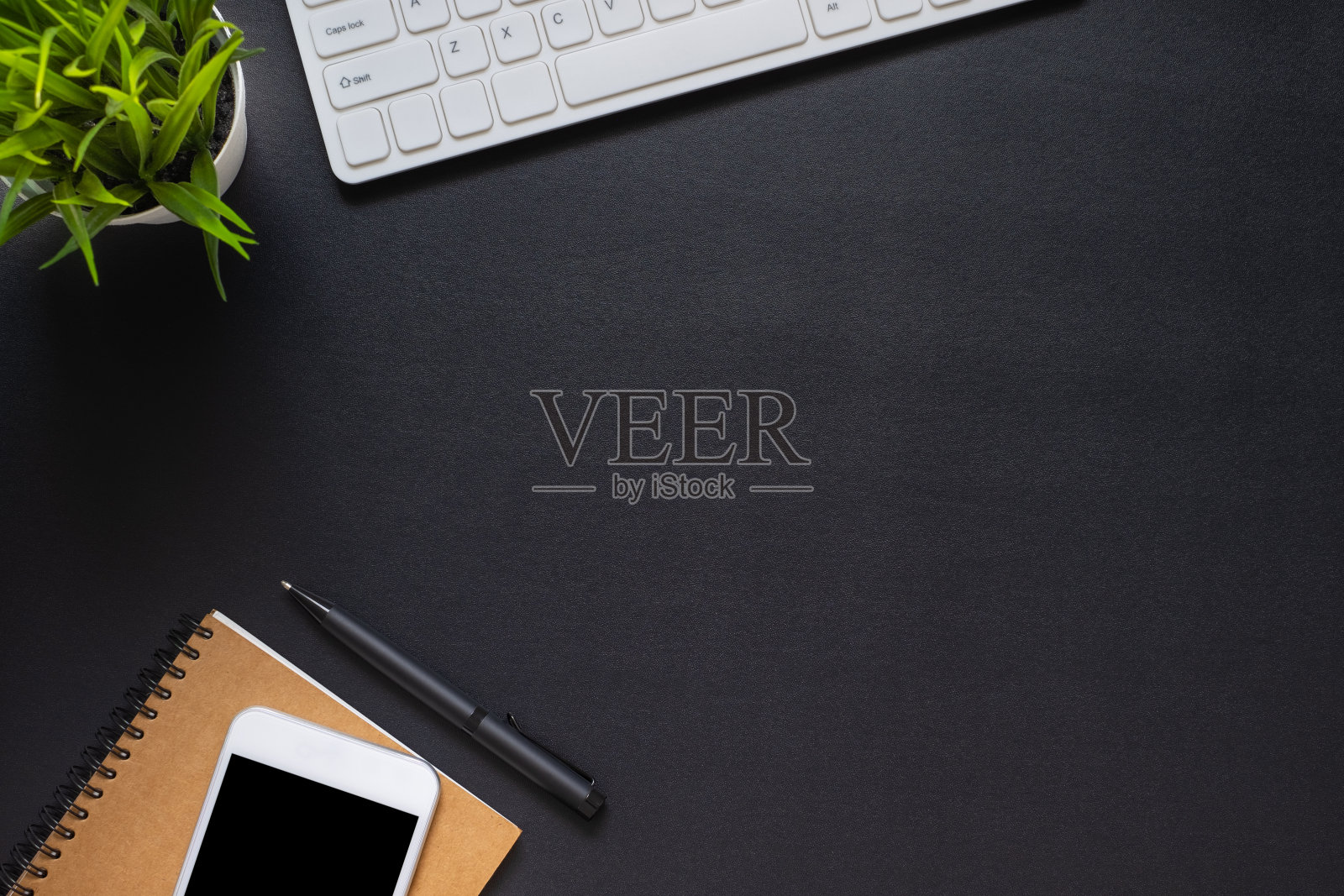 办公室黑色办公桌。俯视图从上面的键盘与笔记本和手机。空间为现代设计师的创意作品。平铺与空白拷贝空间。商业和财务概念。照片摄影图片