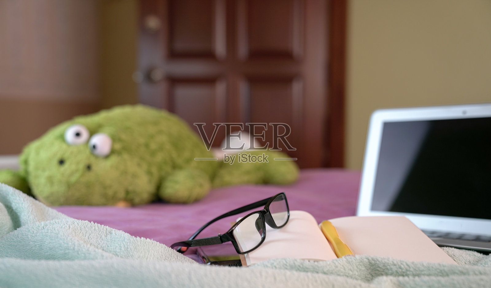 把眼镜放在笔记本上，把笔记本放在床上。在家工作的概念。照片摄影图片