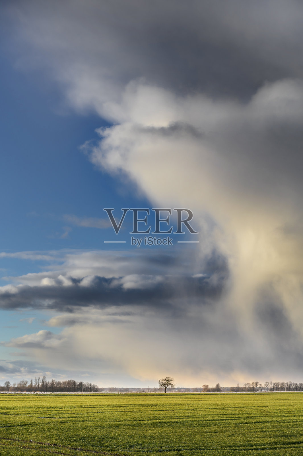 风暴云在日落时形成，大的绿色领域在前景。照片摄影图片