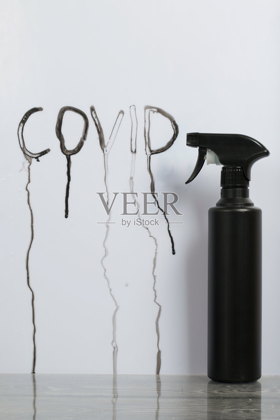 黑色塑料喷枪。消毒剂。白色背景上的一束浪花后面流淌着懦弱的碑文。照片摄影图片