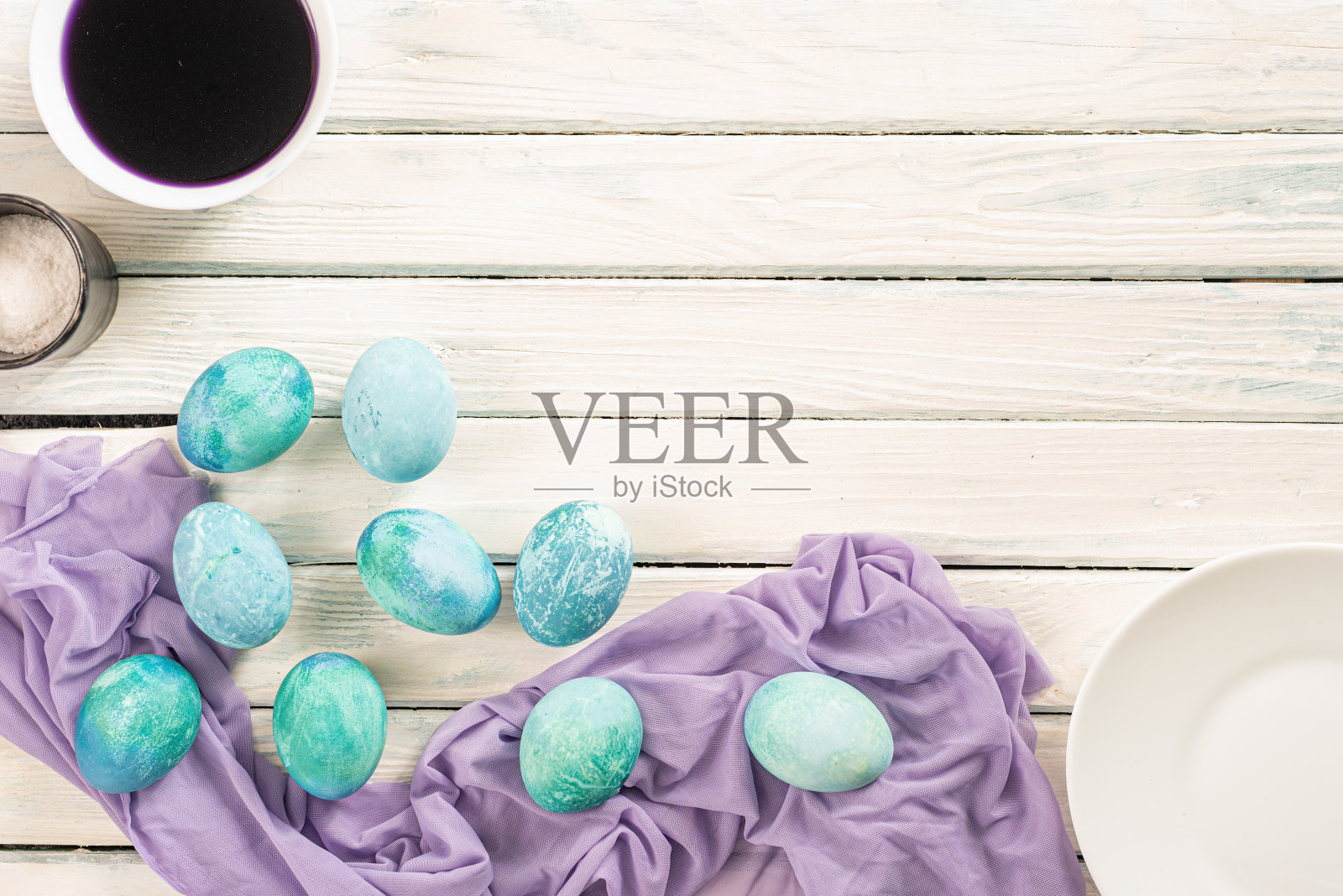 白色背景的黄色盘子上摆放着蓝色大理石彩蛋，这是复活节的象征照片摄影图片