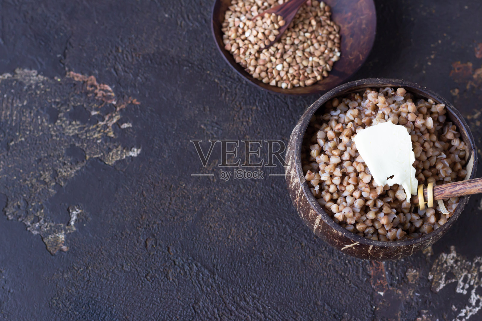椰子碗与美味的煮荞麦和生的有机荞麦谷物椰子碗，深棕色的混凝土背景。无谷蛋白，健康饮食。照片摄影图片