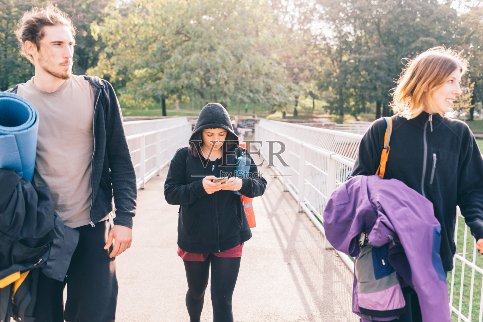 三个年轻漂亮的白人运动朋友在城市户外散步背光聊天照片摄影图片