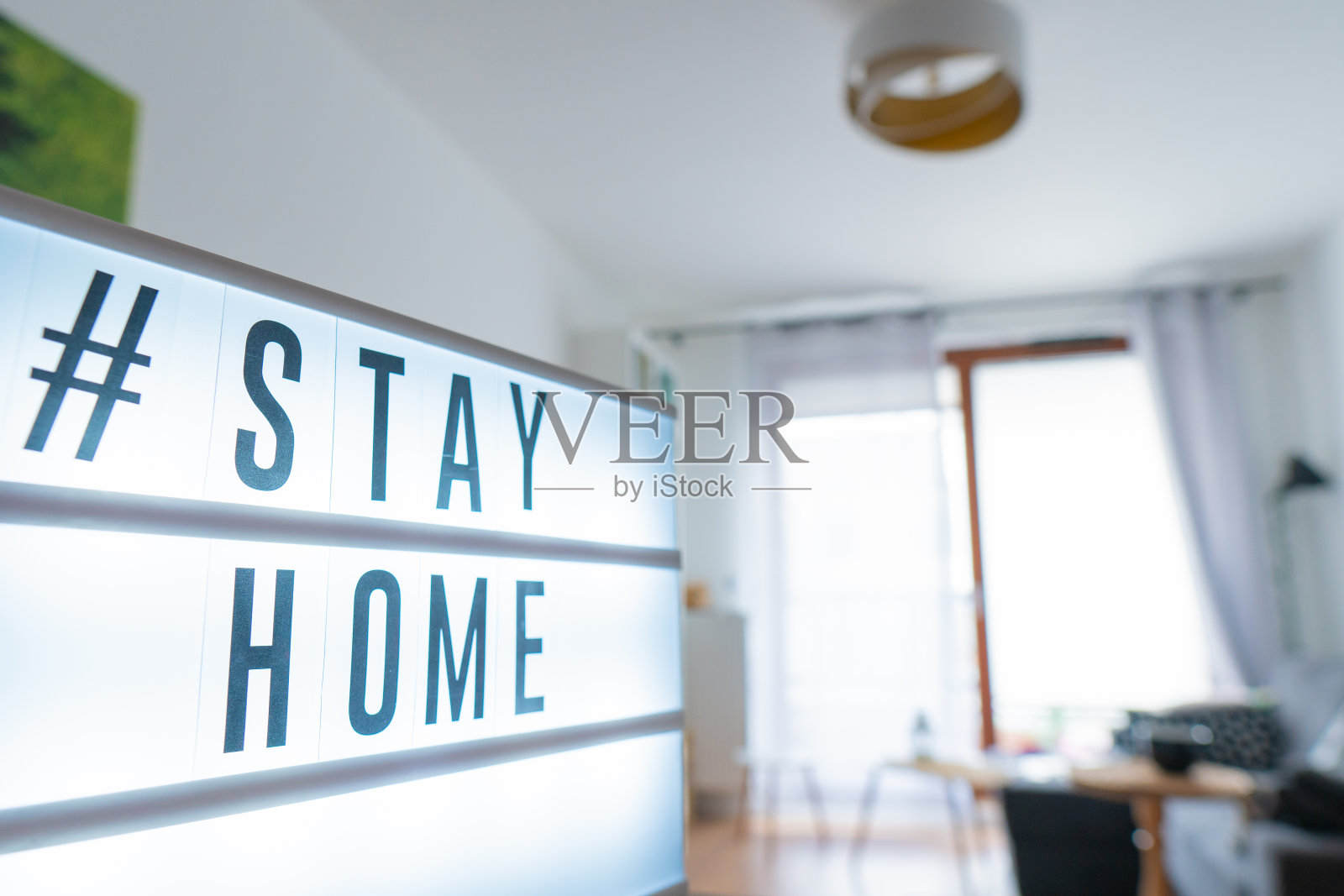 冠状病毒家庭标识灯箱，文字标签#待在家里发光。新冠肺炎疫情宣传横幅公寓的背景照片摄影图片