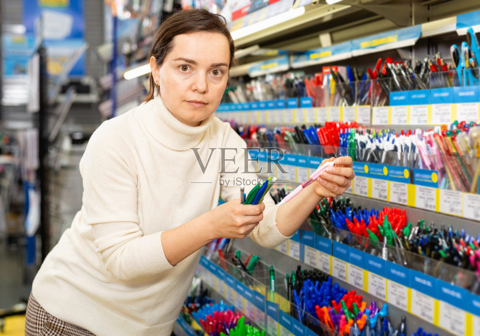 在文具店选购圆珠笔的女人肖像照片摄影图片