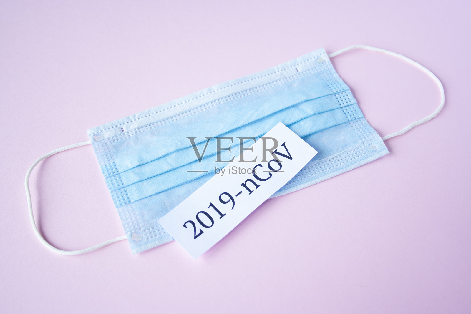 粉色背景的医用口罩上的题词是2019-ncov。冠状病毒治疗的概念。药物病毒疫苗照片摄影图片