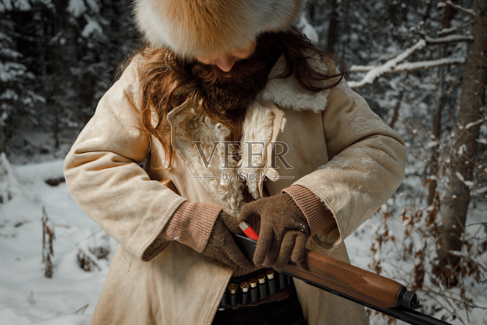 穿着复古衣服、留着胡子的野蛮猎人在枪里装弹药照片摄影图片