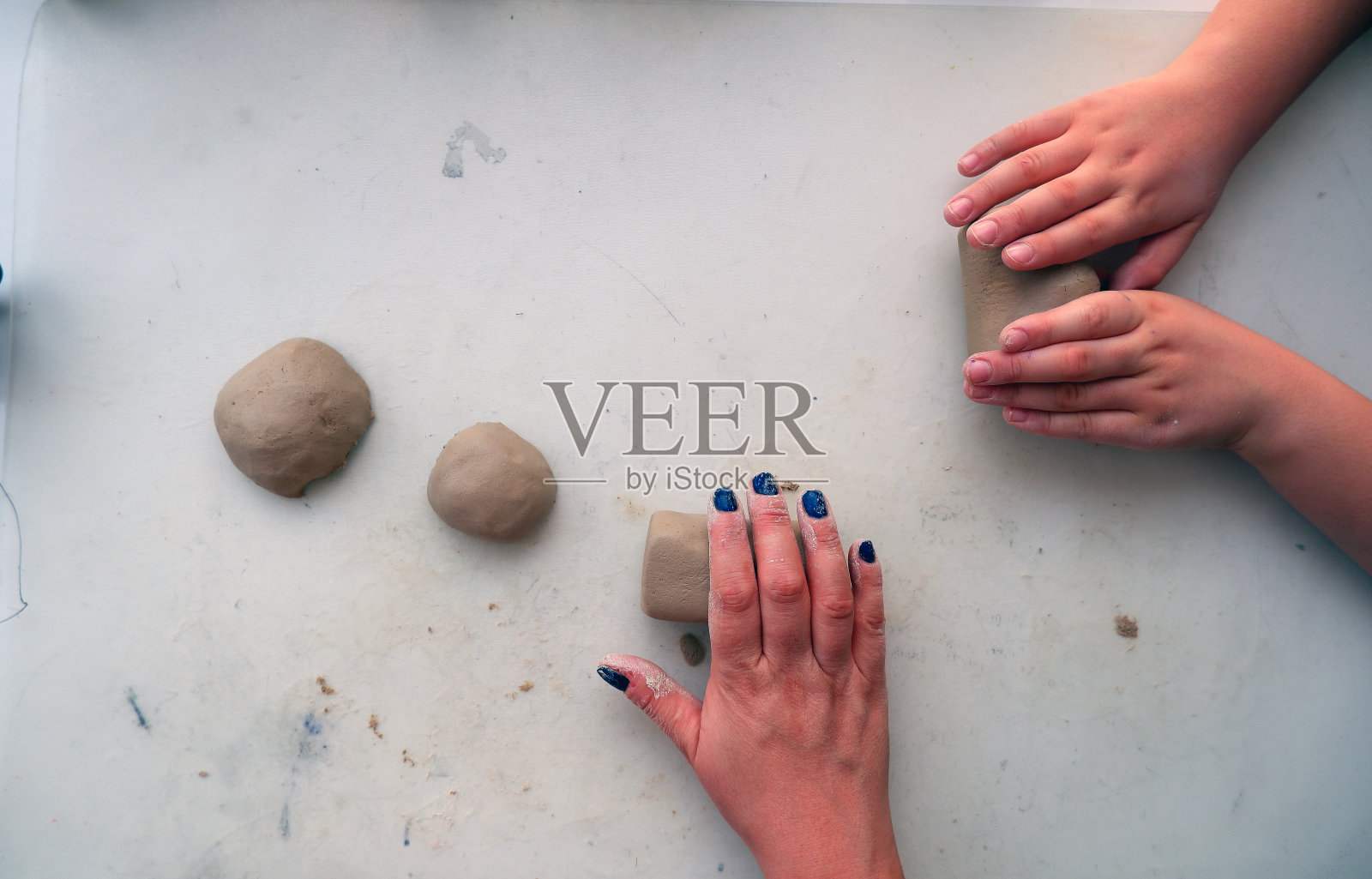 母亲和儿子的双手塑造着房子里的泥土。照片摄影图片