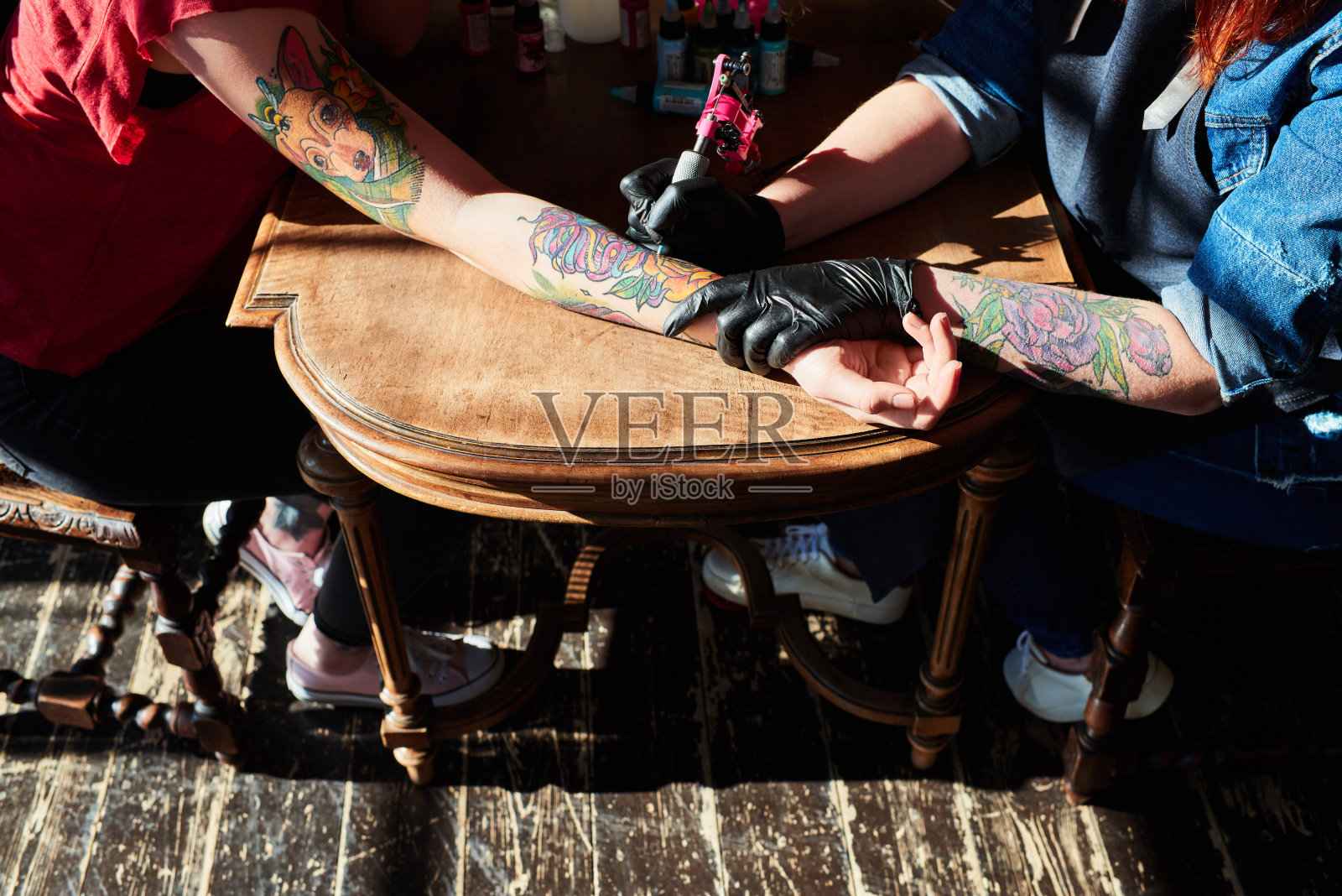 高角度的年轻女子在专业纹身工作室的手臂上进行彩色纹身，精通电动纹身机的工作照片摄影图片