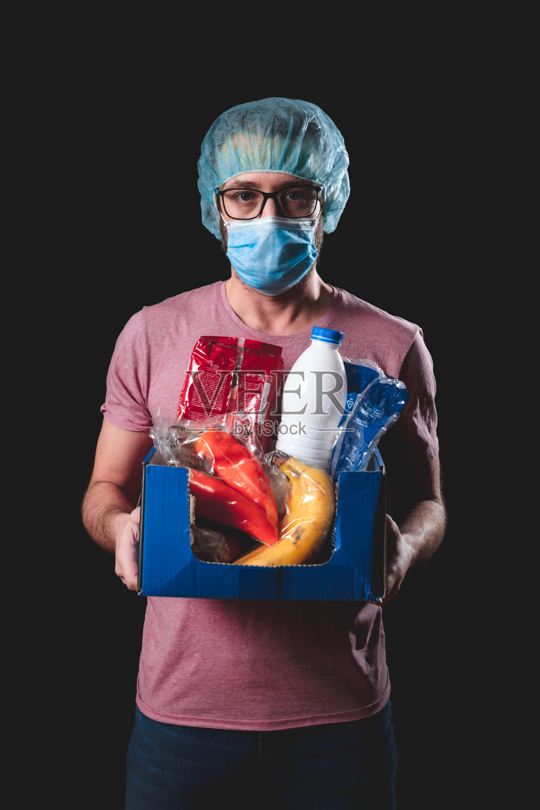 食品和杂货送货上门，大流行爆发，穿着制服的人拿着一个装着用品的盒子。照片摄影图片