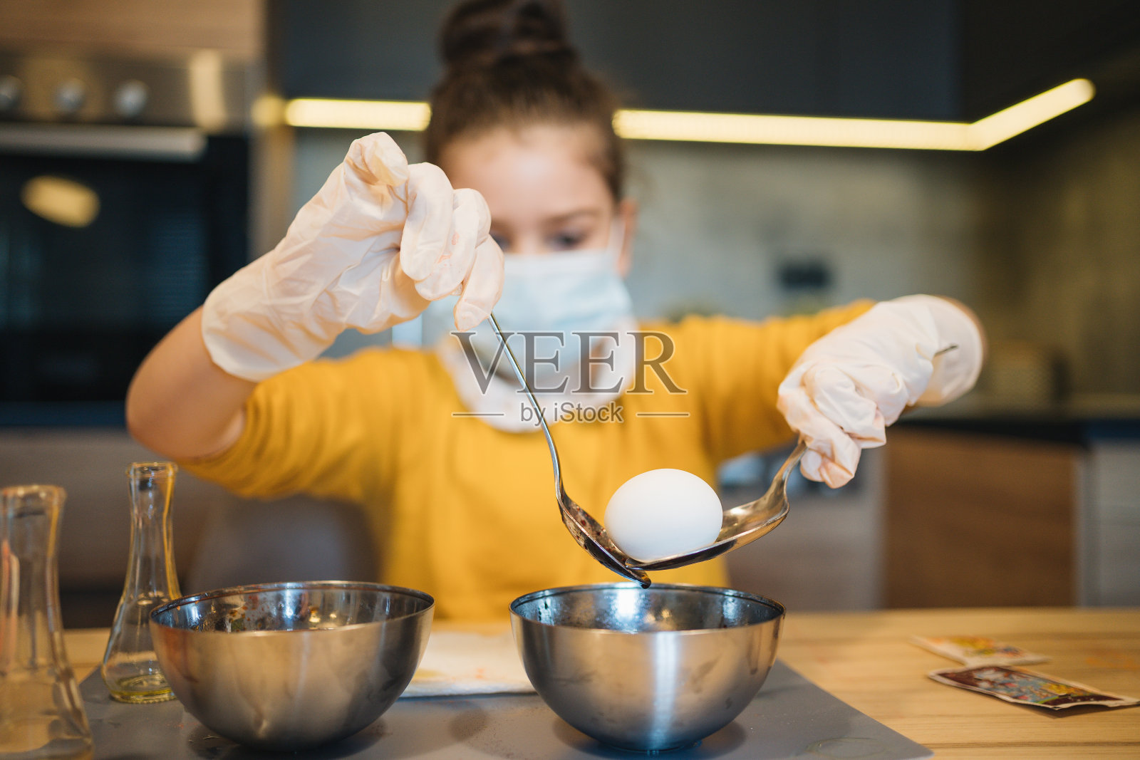 在流行病期间，戴着防护面具的女孩画复活节彩蛋照片摄影图片