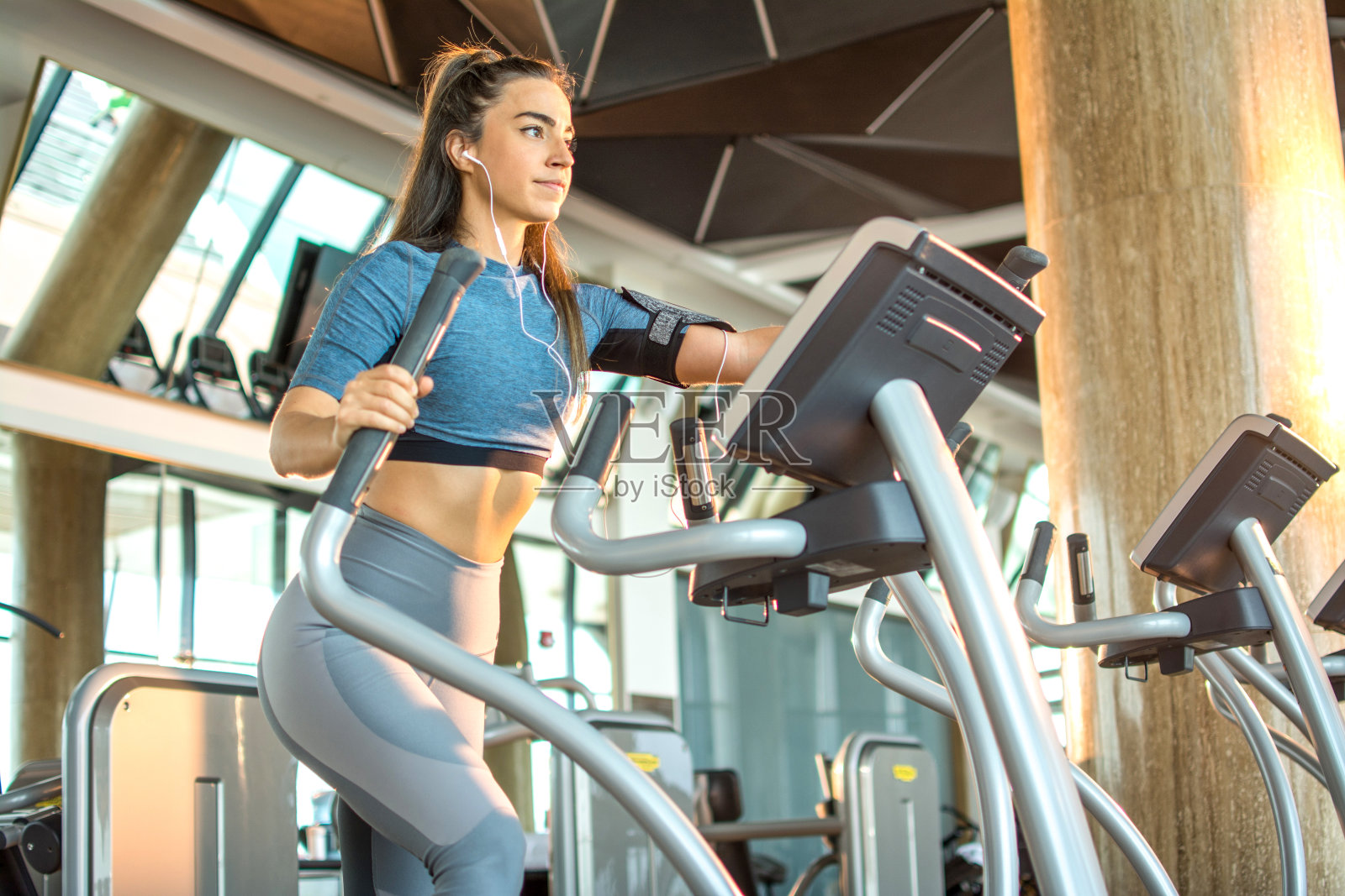 迷人的年轻女性健身在椭圆机健身在健身房照片摄影图片