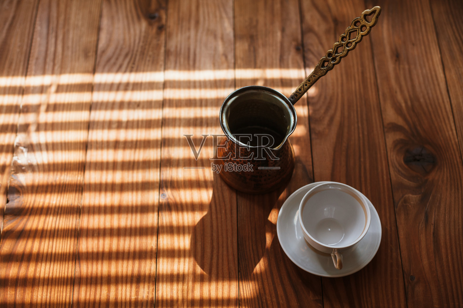 传统的土耳其铜咖啡壶，塞兹韦，伊布里克和白色空瓷杯和茶托，放在一张木桌上，特写。照片摄影图片